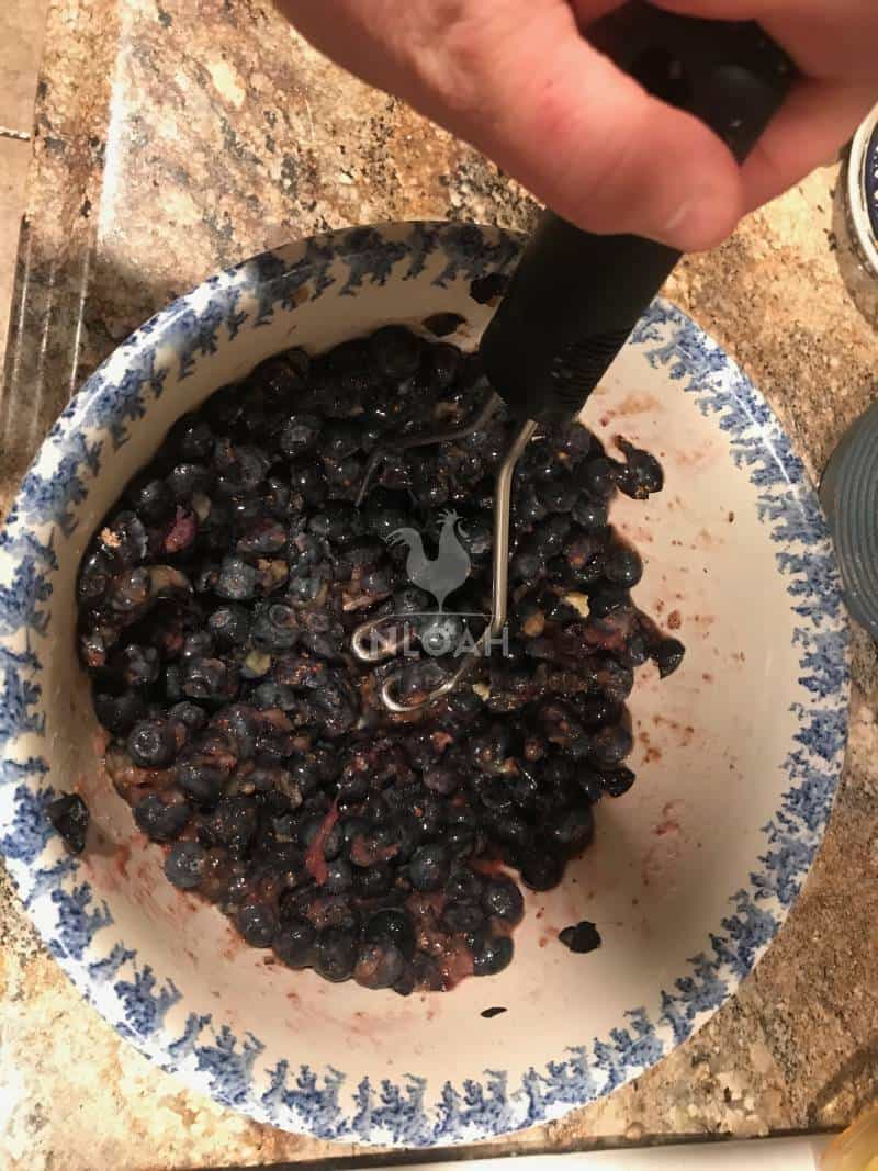 crushing berries to make blueberry jam
