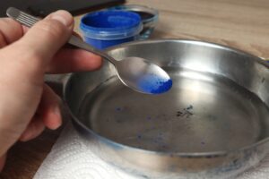 adding mica powder to melted wax with teaspoon