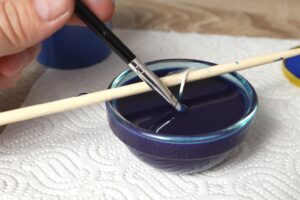 stirring candle mixture with paintbrush