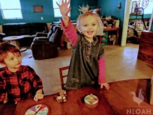 little girl raising hands in homeschool classroom