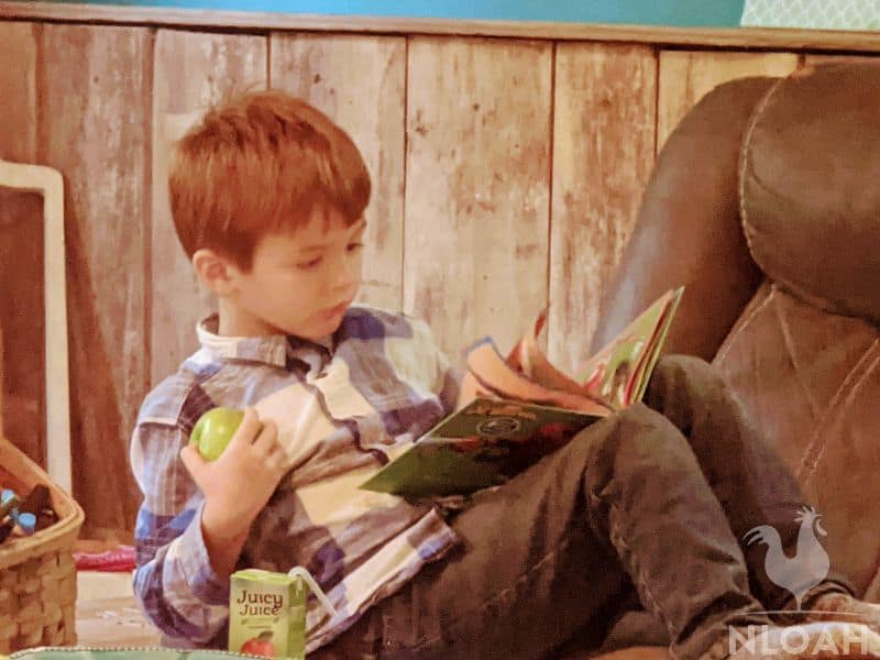 child reading and holding an apple in hand