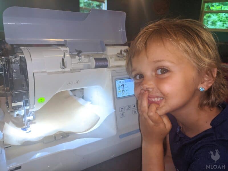 little girl next to sewing machine