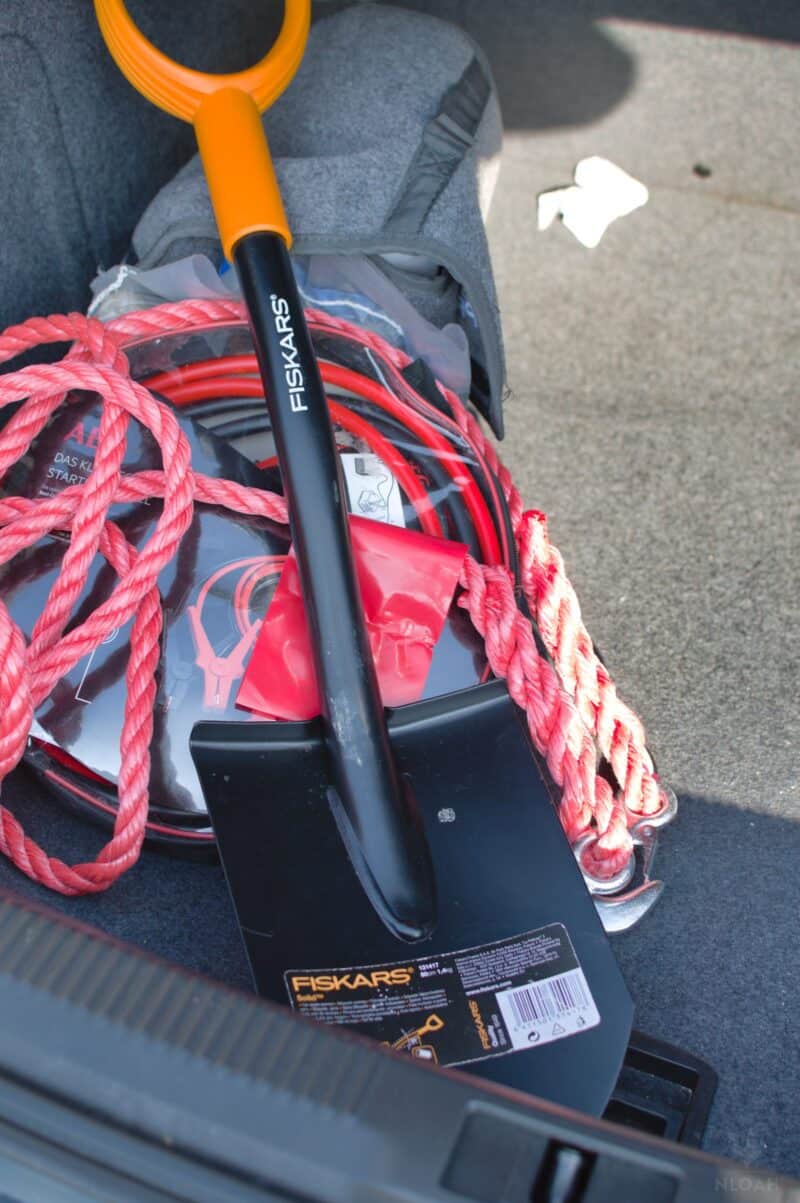 jumper cables and snow shovel in car trunk