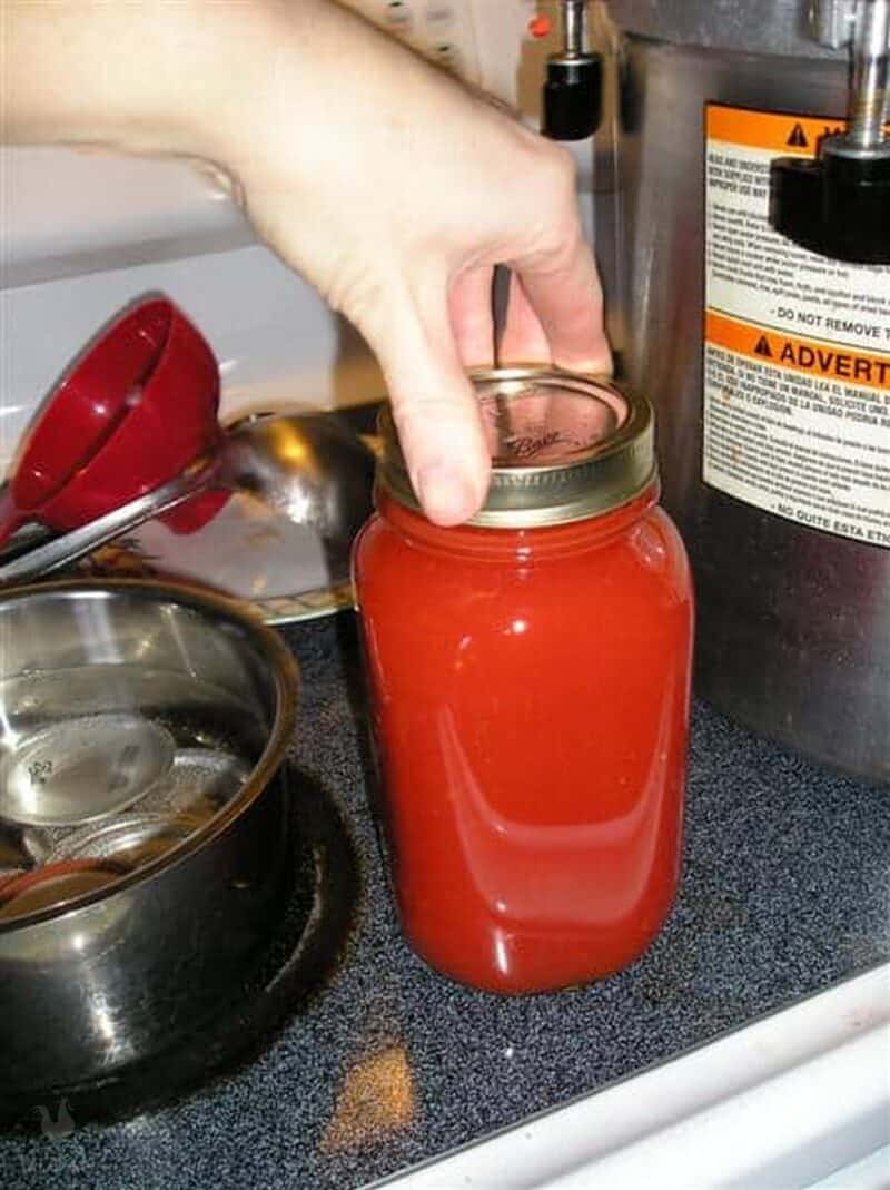 screwing lid on jar of canned tomato juice