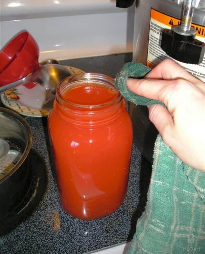 wiping jar filled with tomato juice with cloth