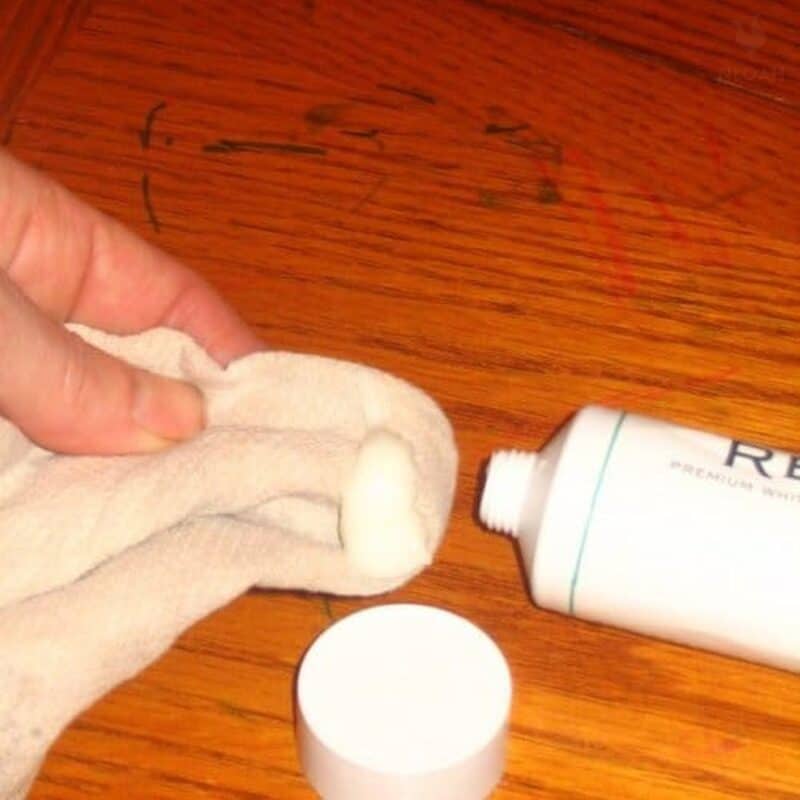 applying toothpaste to wooden table scribbled with marker