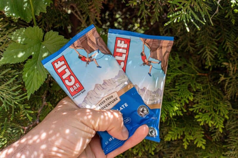 holding two clif bars in the forest