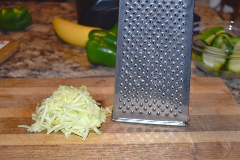 shredded zucchini next to cheese grater