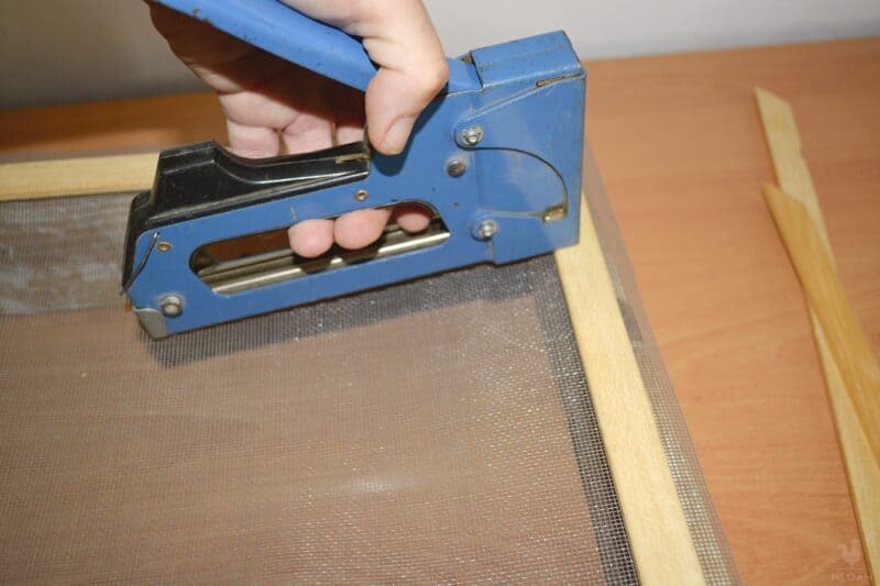 attaching the trim frame and the netting using the staple gun