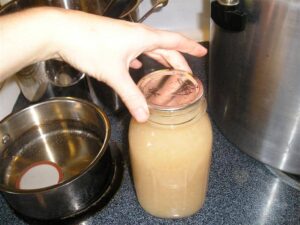 putting lid on jar with pear sauce