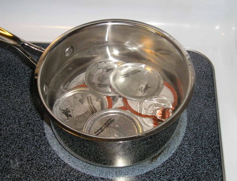 sanitizing canning lids in simmering pot of water