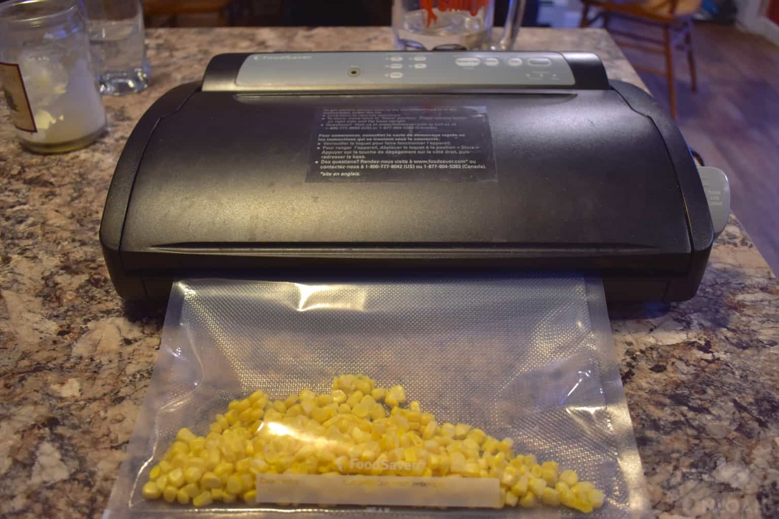 frozen corn kernels in zipper bag next to vacuum sealer