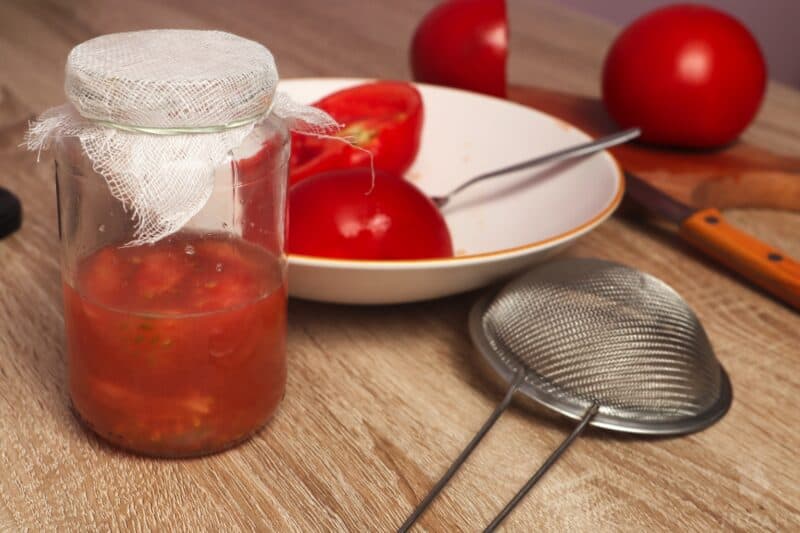 tomato flesh and seeds covered in water in glass jar