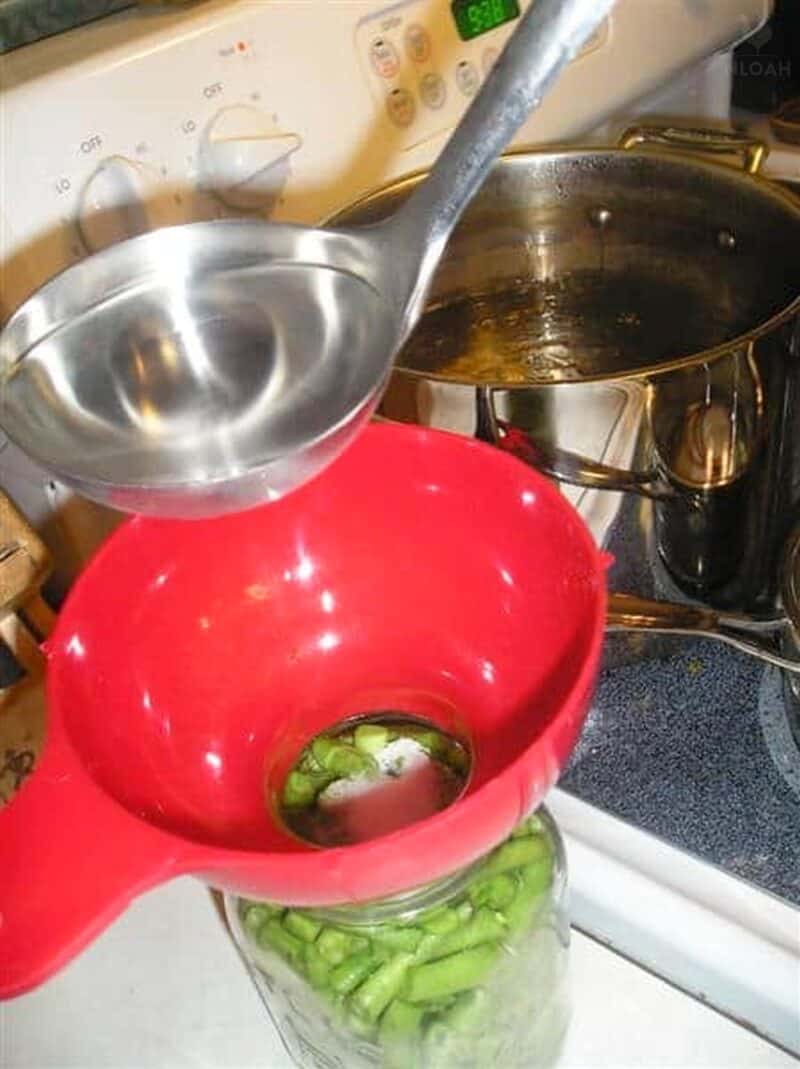 adding boiling water in canning jar with ladle