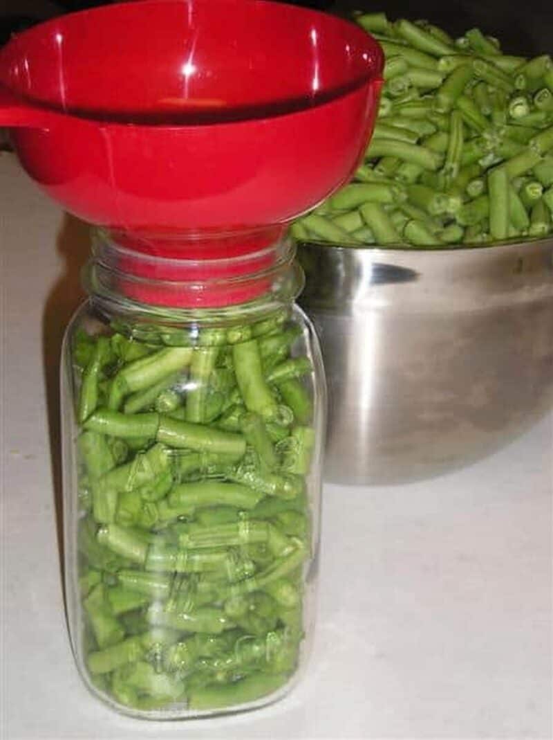 filling canning jar with green beans