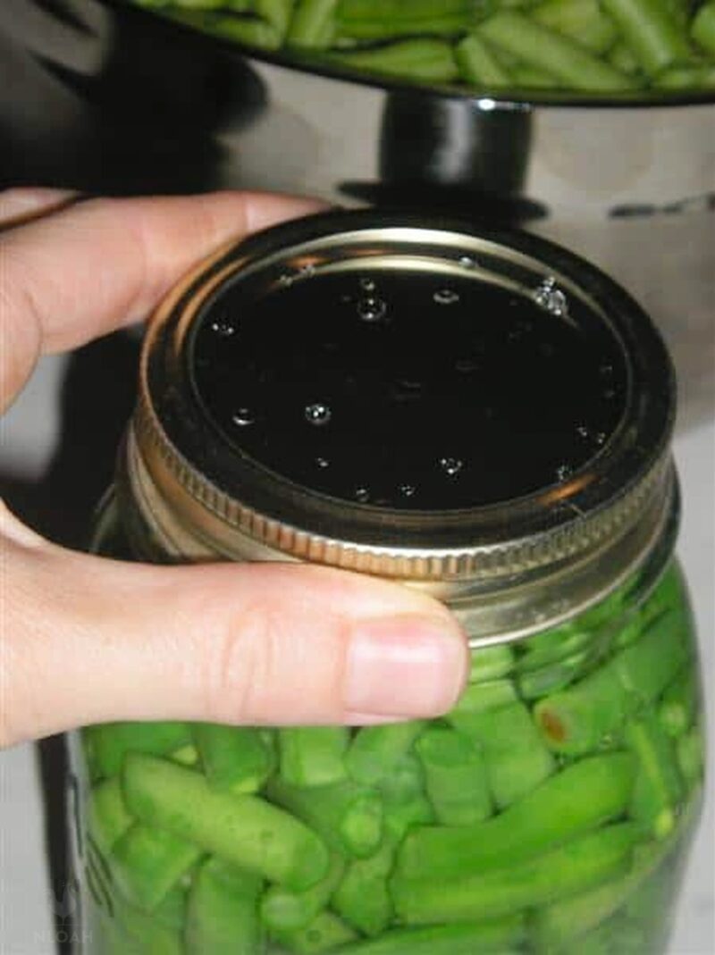 placing a canning ring over canning jar and lid