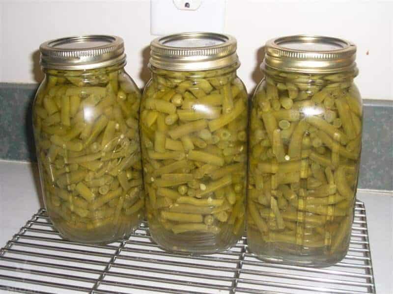 three jars of canned green beans on cooling rack