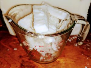 chunks of soap base in a measuring cup