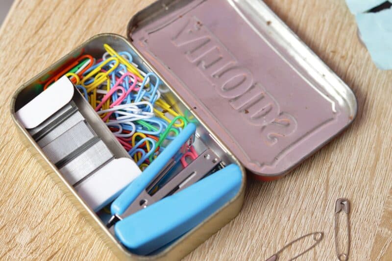 paper clips, stapler, and staples inside Altoids tin