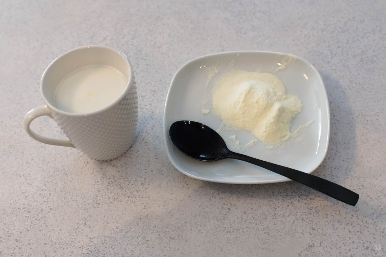 powder milk on small plate next to mug with reconstituted milk