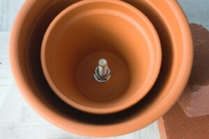 the two clay pots tightened together with nuts and bolts