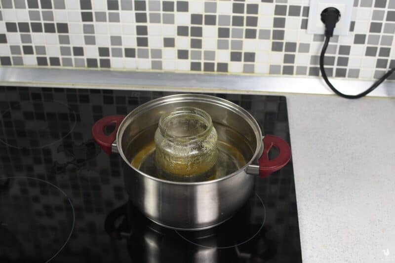 jar of honey inside saucepan half-full with boiled water