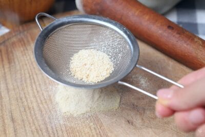 sifting garlic powder through metal strainer