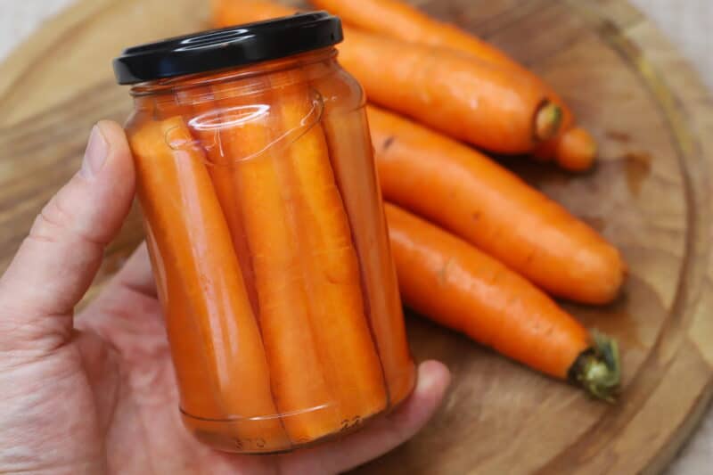 holding a jar of pickled carrots