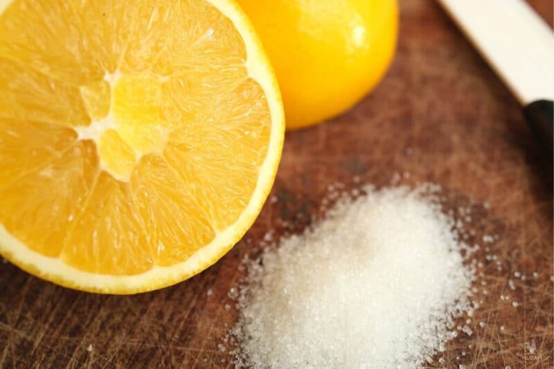 orange cut in half next to some sugar