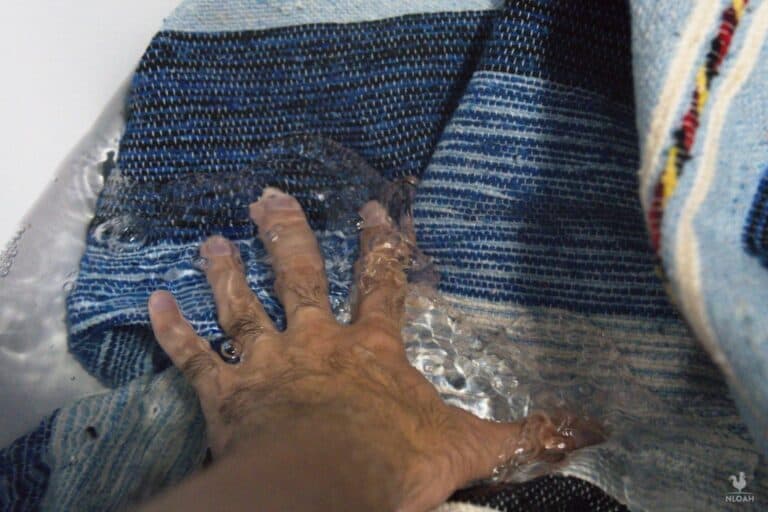 submerging wool blanket in water with hand